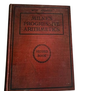 May include: A vintage hardcover textbook titled Milne's Progressive Arithmetics, Second Book, With Answers. The book features a dark red, textured cloth cover with black border lines and black printed text centered on the front cover.