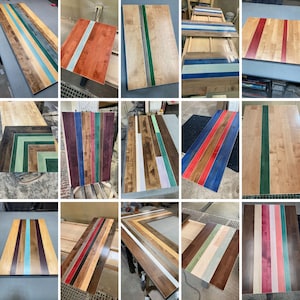 May include: A collection of rectangular wooden panels featuring various inlaid colored resin strips. The designs include vertical, horizontal, and chevron patterns in shades of red, blue, green, purple, and white, showcasing natural wood grain.