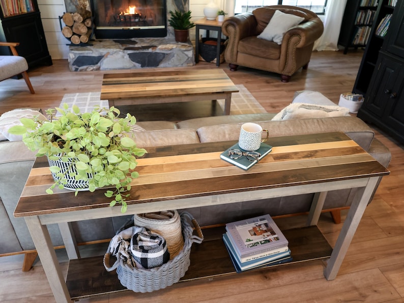 a cozy living room with a fireplace, a wooden coffee table, and a comfortable couch. The coffee table has a plant, a mug, and some books on it, creating a welcoming atmosphere.