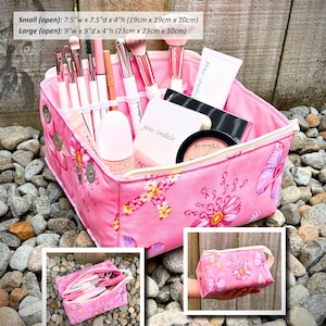 May include: Pink floral makeup caddy with a zipper closure, filled with makeup brushes, cosmetics, and skincare products. The caddy is available in two sizes: 7.5"w x 7.5"d x 4"h and 9"w x 9"d x 4"h. The text "Be You Makeup Caddy" is visible.