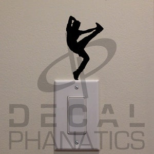 May include: A black silhouette of a person doing a dance move on a white light switch. The switch is labeled "DECAL PHANATICS".