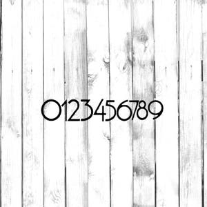 May include: Black numbers 0 through 9 are painted on a white wooden surface.