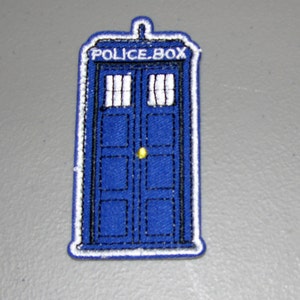 May include: Blue and white embroidered patch of a police box with the text "POLICE BOX" on the front.