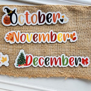 Puede incluir: Tres letreros rectangulares blancos con ilustraciones coloridas de tem&aacute;tica oto&ntilde;al y las palabras "Octubre", "Noviembre" y "Diciembre".