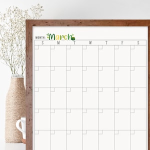 May include: A white dry-erase calendar with a brown wood frame. The calendar is labeled "March" with a green shamrock design. The calendar has a grid of squares for each day of the month, labeled with the days of the week: Sunday, Monday, Tuesday, Wednesday, Thursday, Friday, and Saturday.