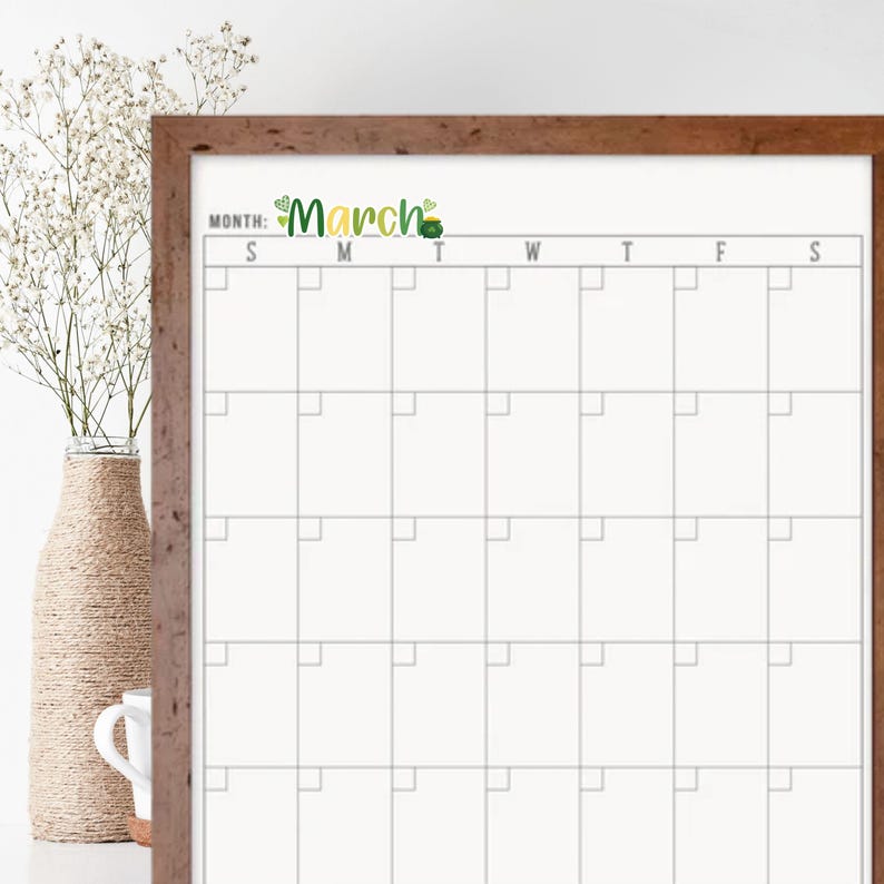 May include: A white dry-erase calendar with a brown wood frame. The calendar is labeled "March" with a green shamrock design. The calendar has a grid of squares for each day of the month, labeled with the days of the week: Sunday, Monday, Tuesday, Wednesday, Thursday, Friday, and Saturday.