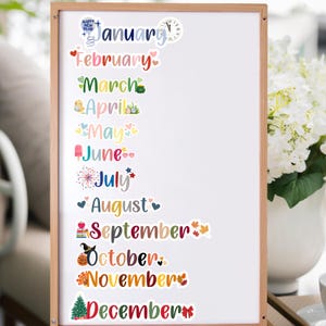 Puede incluir: Una pizarra blanca con pegatinas de calendario mensual de colores. Cada mes est&aacute; decorado con una ilustraci&oacute;n diferente, como un reloj, un pollito, una paleta de helado, fuegos artificiales y un &aacute;rbol de Navidad.