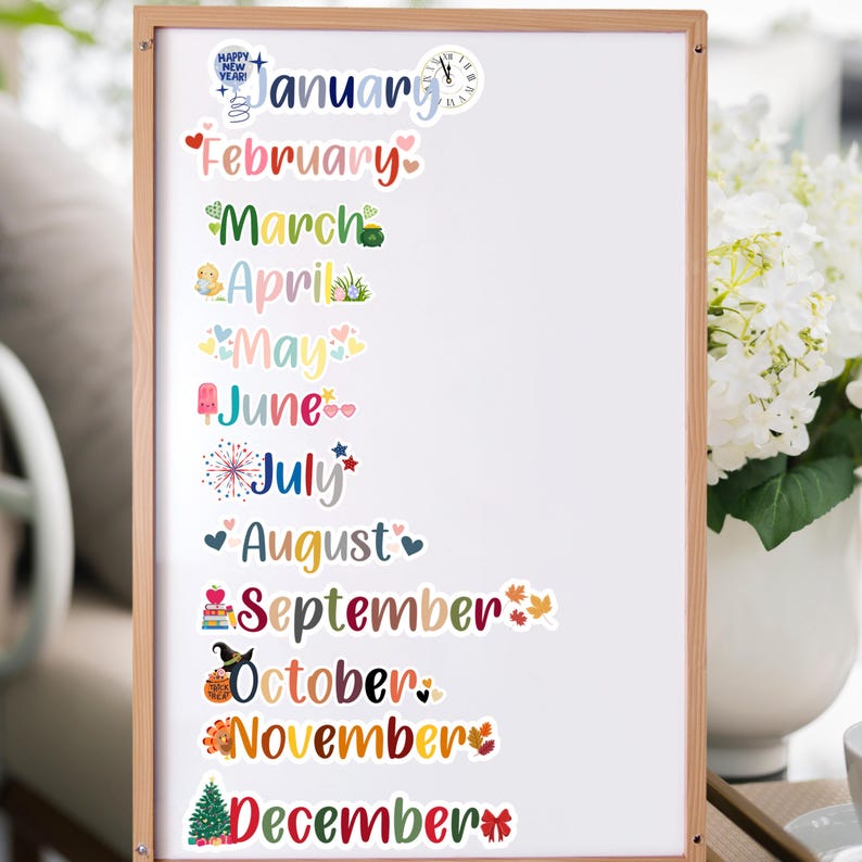 Puede incluir: Una pizarra blanca con pegatinas de calendario mensual de colores. Cada mes est&aacute; decorado con una ilustraci&oacute;n diferente, como un reloj, un pollito, una paleta de helado, fuegos artificiales y un &aacute;rbol de Navidad.