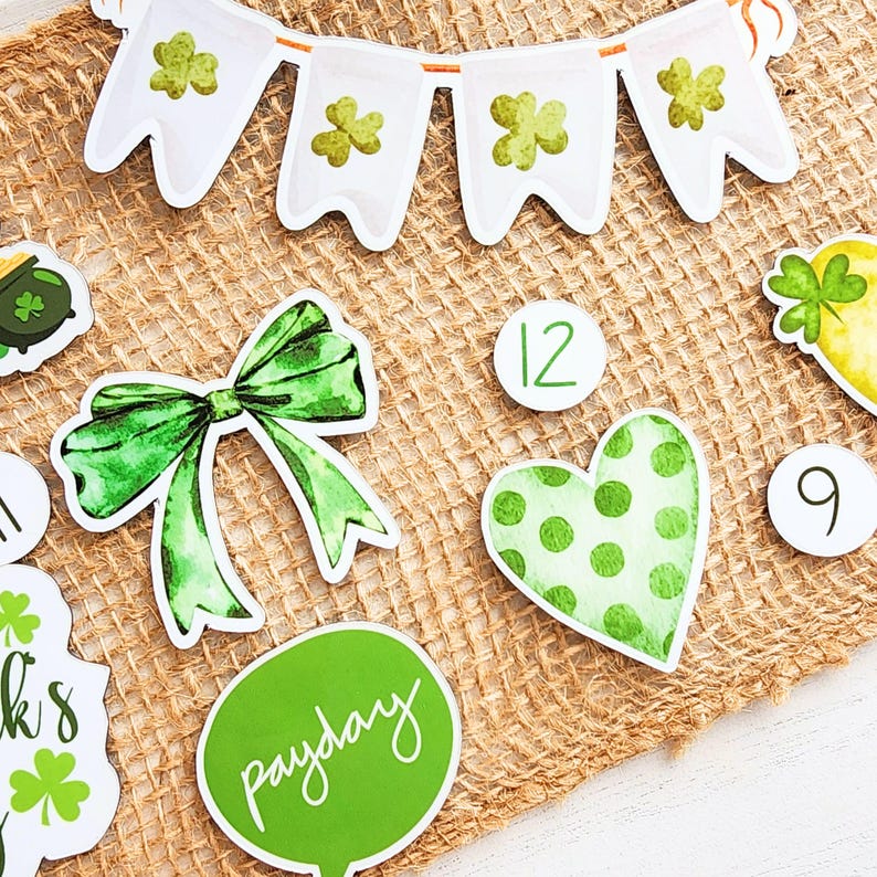 May include: Green and white St. Patrick's Day themed decorations on a burlap background. The decorations include a banner, a bow, a heart, a pot of gold, and numbers 9 and 12. The banner has shamrocks and the text "Payday".