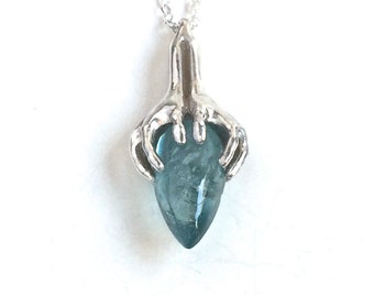 Aquamarine pendant, hands holding a teardrop cut aquamarine stone