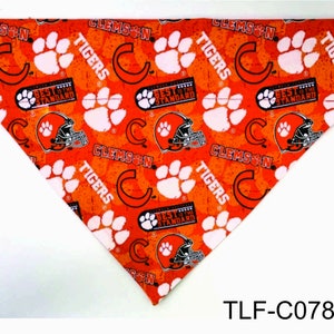 May include: Orange and white dog bandana with a Clemson Tigers logo and paw prints. The bandana has the text "Clemson Tigers" and "Best of the Standard" repeated throughout the design.