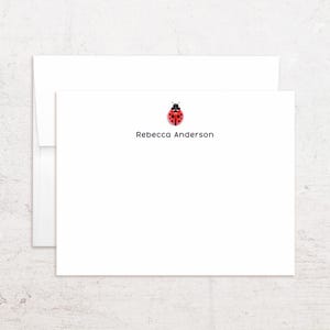 May include: White stationery set featuring a ladybug design. The stationery includes a card and envelope. The card has the name "Rebecca Anderson" printed below the ladybug illustration. The ladybug is red with black spots and a black head.