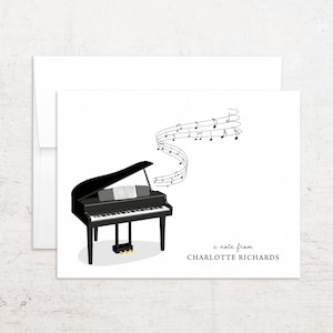 May include: A black grand piano illustration with musical notes flowing upwards. The piano has a white keyboard and a music sheet on the stand. The text "a note from CHARLOTTE RICHARDS" is printed on the card.