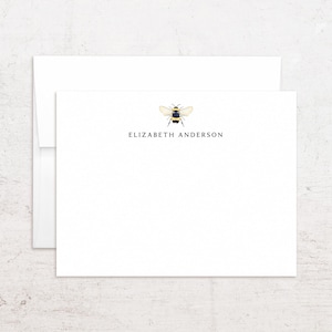 May include: White stationery set featuring a watercolor illustration of a bee. The stationery includes a card and envelope, with the name "ELIZABETH ANDERSON" printed in black. The bee is yellow, black, and white.