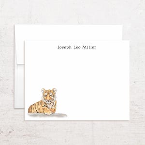 May include: White stationery set featuring a watercolor illustration of a tiger cub. The text "Joseph Leo Miller" is printed at the top. The set includes a folded card and an envelope.