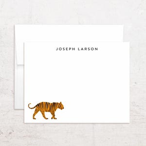 May include: White stationery set featuring a minimalist design. The stationery includes a card and envelope. The card has the name "JOSEPH LARSON" printed at the top and a stylized orange and black tiger illustration at the bottom.