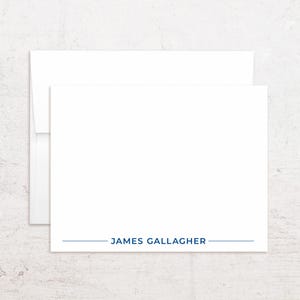 May include: White stationery set with a matching envelope. The card features the name "JAMES GALLAGHER" in navy blue text with a navy blue line underneath. The stationery is on a white background.