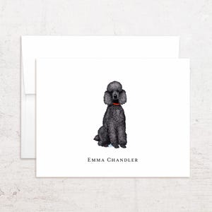 May include: A white stationery card with a black poodle illustration wearing a red collar. The card has the text "EMMA CHANDLER" at the bottom. A white envelope is behind the card.