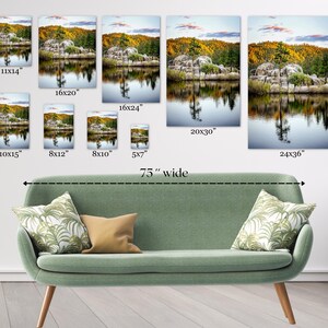 May include: Various sizes of landscape art prints are displayed above a green sofa. The prints depict a serene lake scene with trees and reflections. The largest print is 24x36 inches, and the sofa is 75 inches wide.