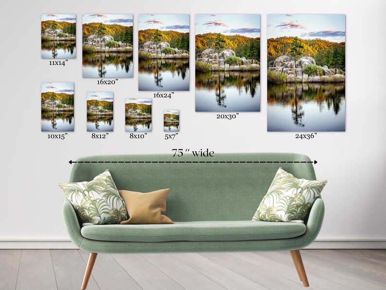 May include: Various sizes of landscape art prints are displayed above a green sofa. The prints depict a serene lake scene with trees and reflections. The largest print is 24x36 inches, and the sofa is 75 inches wide.