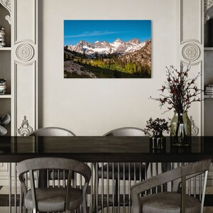 Puede incluir: Una fotograf&iacute;a panor&aacute;mica de una cordillera con picos cubiertos de nieve y un valle verde exuberante en primer plano. El cielo es azul brillante con algunas nubes.