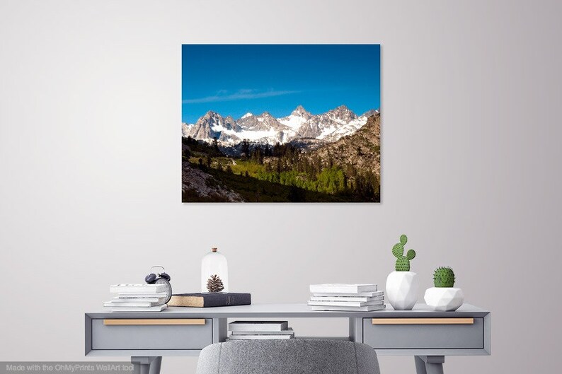 Puede incluir: Una fotograf&iacute;a panor&aacute;mica de una cordillera con picos cubiertos de nieve y un valle verde exuberante en primer plano. El cielo es azul brillante con algunas nubes.