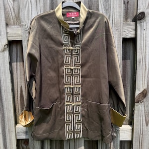 May include: A long-sleeved jacket in a metallic bronze-brown hue featuring a mandarin collar, gold-toned cuffs, and a front closure with five decorative frog fasteners. The placket is adorned with a cream-colored geometric Greek key pattern.
