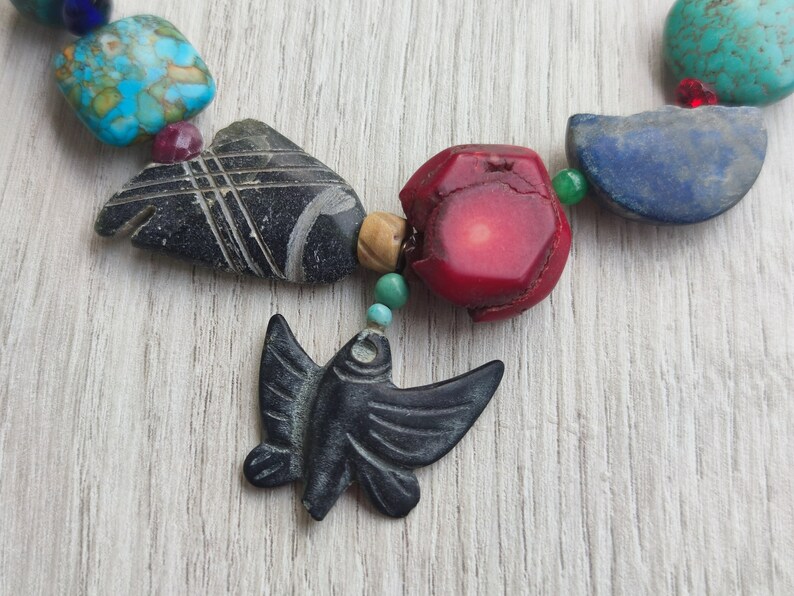 Peut inclure: Un collier de perles color&eacute;es avec un pendentif en forme de papillon en pierre noire sculpt&eacute;e. Le collier est compos&eacute; de perles turquoise, rouges, bleues et vertes.