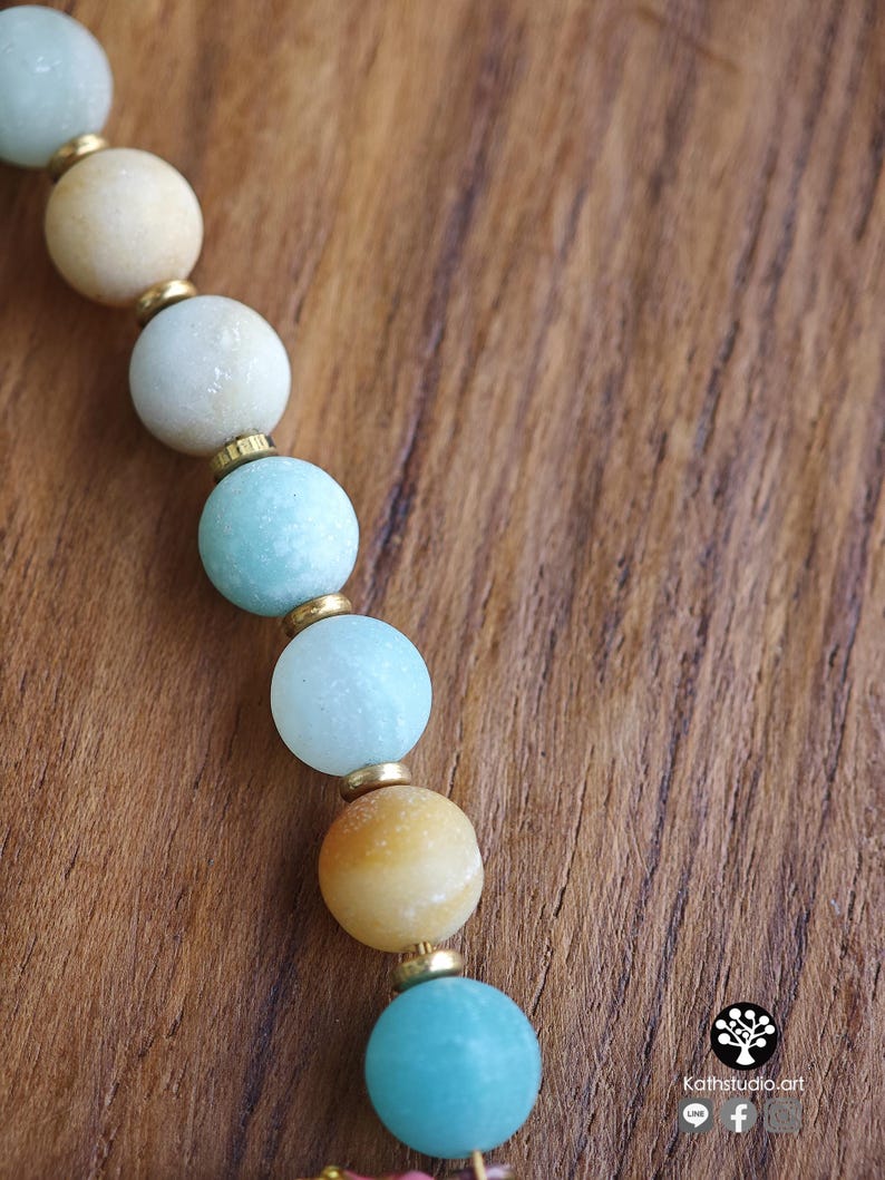 May include: A beaded strand featuring alternating round light blue, turquoise, and pale yellow beads separated by small gold-toned metal spacers. The beads have a matte, textured finish. The text Kathstudio.art is visible in the bottom corner.
