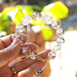 May include: A bracelet featuring clear, spherical crystal beads interspersed with gold-toned metal spacers and two carved, translucent crystal figures. The design includes a gold-toned metal clasp closure. The image includes the text Kathstudio.art.