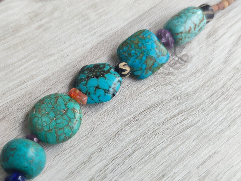 Peut inclure: Un collier de perles turquoise et brun avec des perles carr&eacute;es et rondes. Les perles ont un motif marbr&eacute;.