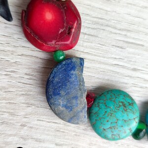 Peut inclure: Gros plan sur un collier avec des perles rouges, bleues, vertes et turquoise. Les perles sont faites de diff&eacute;rents mat&eacute;riaux, dont le corail, le lapis-lazuli et la turquoise.