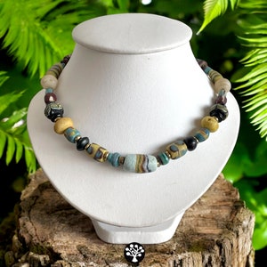 May include: A necklace made of colorful glass beads, including blue, yellow, and black beads. The necklace has a larger, striped, light blue bead in the center.