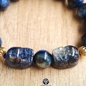 Pu&ograve; includere: Un braccialetto con perline di cianite blu lucide, due figure di animali intagliate in cianite e distanziatori in metallo dorato. Le perline mostrano tonalit&agrave; blu intenso con inclusioni naturali. Il testo Kathstudio.art &egrave; visibile in basso.