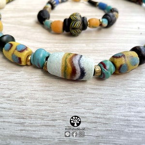 May include: A colorful beaded necklace with a variety of blue, yellow, and white glass beads. The necklace is made of vintage glass beads and has a unique, bohemian style.