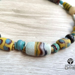 May include: A colorful necklace made of various glass beads, including yellow, blue, green, and brown. The beads are strung together on a cord and have a variety of patterns and textures.