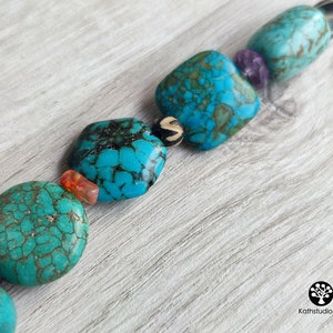 Peut inclure: Un collier de perles turquoise et brun avec des perles carr&eacute;es et rondes. Les perles ont un motif marbr&eacute; et sont enfil&eacute;es sur un cordon brun.
