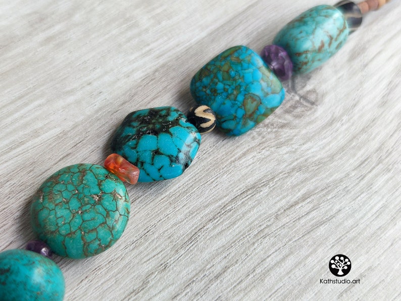 Peut inclure: Un collier de perles turquoise et brun avec des perles carr&eacute;es et rondes. Les perles ont un motif marbr&eacute; et sont enfil&eacute;es sur un cordon brun.