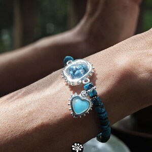 Puede incluir: Una pulsera con cuentas de piedra texturizadas de color azul oscuro y dos dijes plateados. Un dije es un engaste circular de borde festoneado con una piedra azul, y el otro es un engaste en forma de coraz&oacute;n con una piedra azul claro.