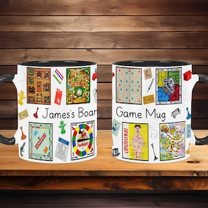 May include: Two black and white ceramic mugs with a personalized name and the text "Game Mug". The mugs feature a collage of classic board game graphics, including Monopoly, Scrabble, Sorry!, Operation, and Twister.