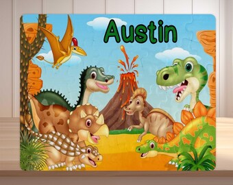 May include: A colorful dinosaur-themed puzzle featuring various cartoon dinosaurs, a volcano, and a flying pterodactyl against a blue sky background. The name "Austin" is written in green letters across the top. This puzzle is designed for children.