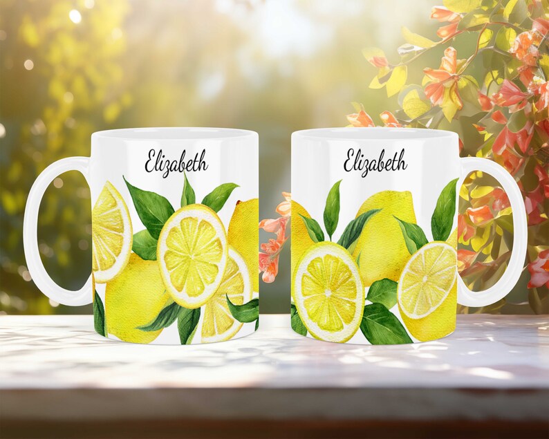 May include: Two white ceramic mugs with a lemon design. The mugs have the name "Elizabeth" printed on them.