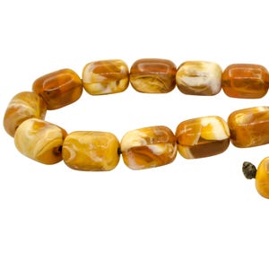 May include: A string of amber beads with a marbled pattern. The beads are a warm brown color with white swirls throughout.
