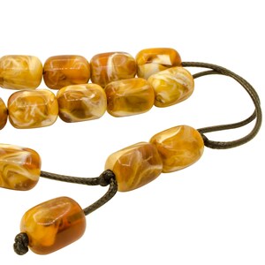 May include: A string of amber-colored beads with white swirls. The beads are connected by a dark brown cord.