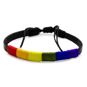 May include: A black leather bracelet with a rainbow-colored woven design. The bracelet features red, orange, yellow, green, blue, and purple threads. The adjustable bracelet has a black knotted closure.