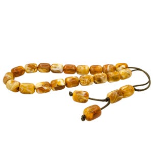 May include: A brown and white prayer beads necklace with a brown tassel. The beads are made of a marbled material.