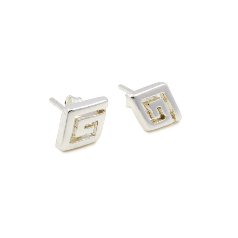 May include: A pair of silver stud earrings with a geometric design. The design is a square with a Greek key pattern inside.