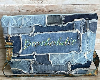 May include: A blue denim tote bag with a patchwork design and the word "Beachholic" embroidered in green and blue. The bag has a long, teal and gold patterned strap.