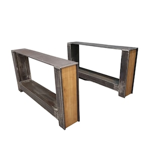 May include: Two metal table legs with a wood accent. The legs are black with a distressed finish. The wood accent is a light brown colour.