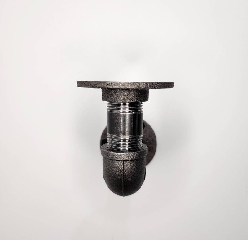 Puede incluir: Soporte de estante de tuber&iacute;a de metal negro con base redonda y parte superior plana. El soporte est&aacute; dise&ntilde;ado para montarse en una pared.